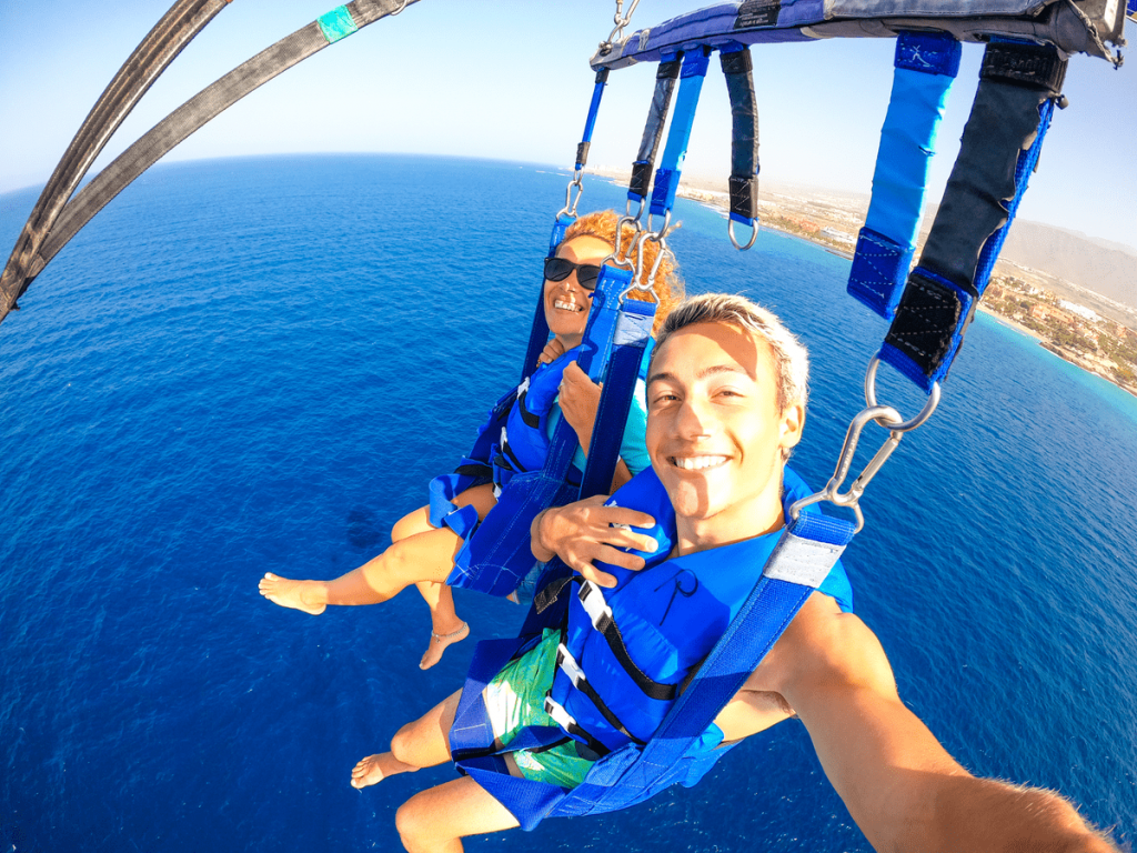 couple-two-happy-people-enjoying-summer-vacations-doing-extreme-activity-sea-with-boat-beautiful-people-taking-selfie-while-doing-parascending-together
